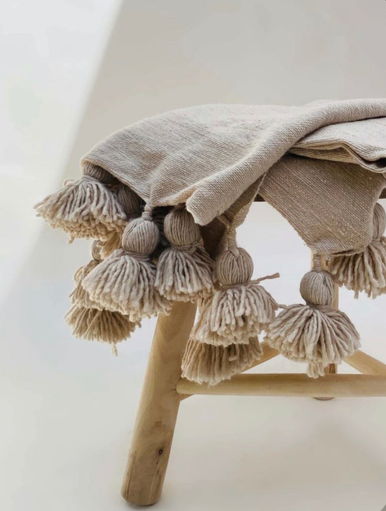 A stunning pom pom blanket throw neutral colors.